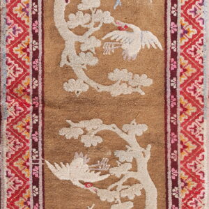 Tan rug depicting a scenic pattern of white trees, stags, and birds, surrounded by thick red geometric borders.