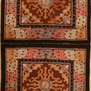 Brown, orange, and beige rug with geometric borders and two stacked panels of dense pile.