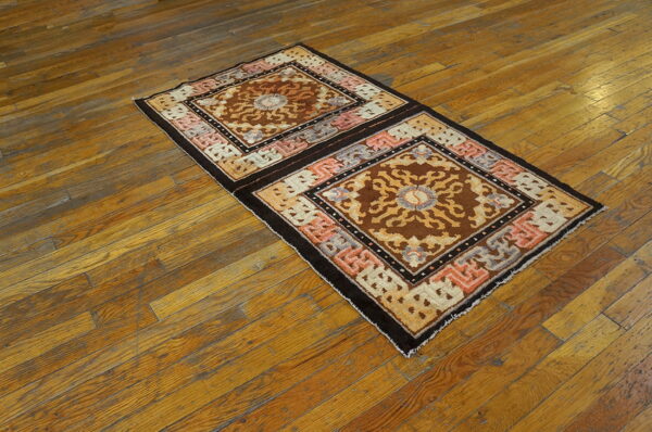 Brown and tan geometric runner rug with pink accents lies diagonally on distressed hardwood flooring.
