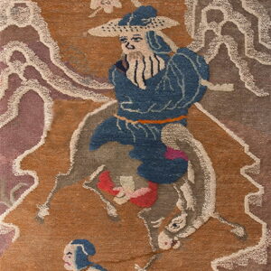 Illustrative rug panel in rust and blue showing figures, a horse, stylized clouds, and pink cherry blossoms.