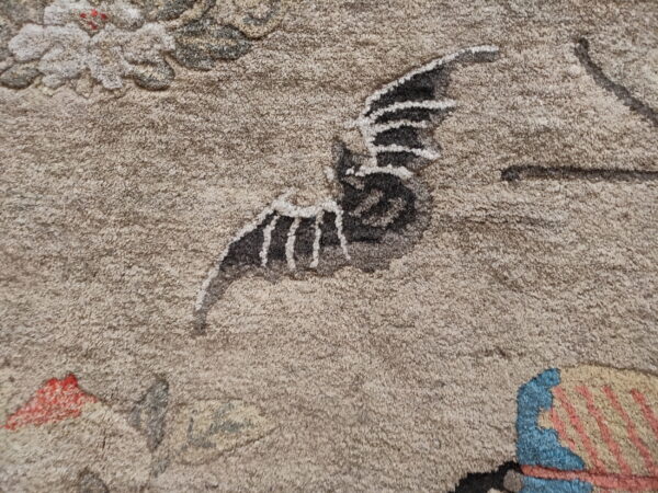 Beige high-pile rug detail showing a gray wing with white stripes, red dots, and striped blue and coral shapes.