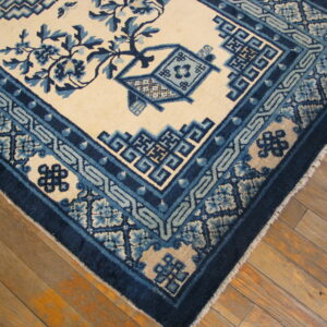 Traditional blue and cream rug with dense floral and geometric border patterns on wood flooring.