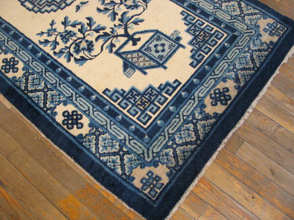 Traditional blue and cream rug with dense floral and geometric border patterns on wood flooring.