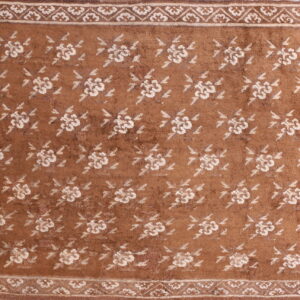 Brown rug featuring an allover pattern of off-white flowers and a detailed floral border.