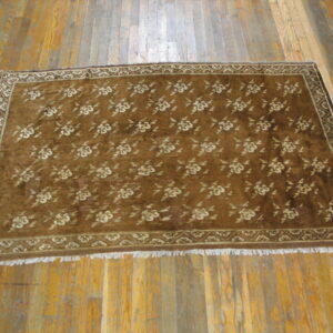Brown plush rug with an all-over repeating cream floral pattern on wood planks.