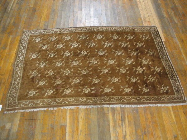Brown plush rug with an all-over repeating cream floral pattern on wood planks.