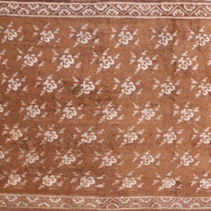 A rust-colored rug featuring repeating cream floral medallions and a detailed multi-layered border.