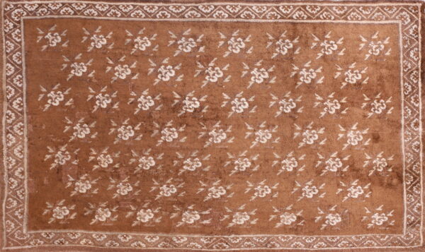 A rust-colored rug featuring repeating cream floral medallions and a detailed multi-layered border.