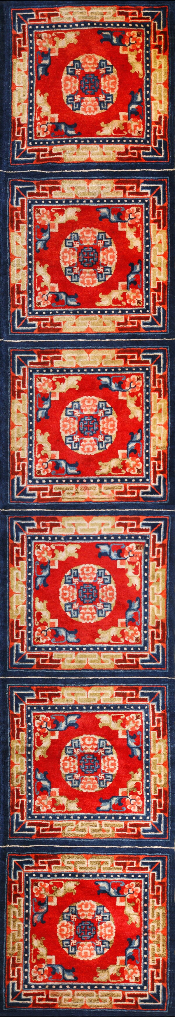 Vertical red rug runner with stacked rectangular panels, indigo borders, and tan geometric accents.