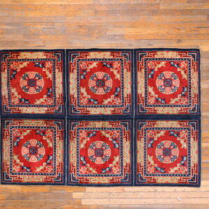This red and blue rug, constructed from six patterned squares, sits on wide-plank hardwood.