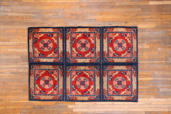 This red and blue rug, constructed from six patterned squares, sits on wide-plank hardwood.