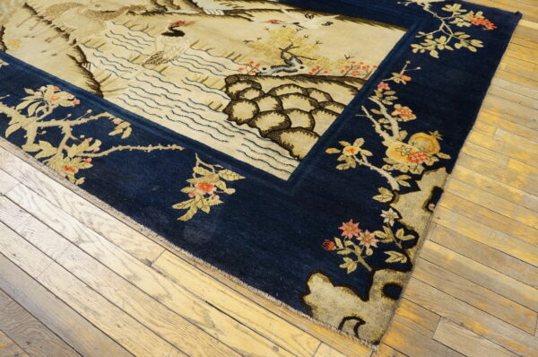 Navy and beige scenic rug with detailed wildlife and floral elements on natural wood flooring.