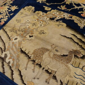 Navy and beige scenic rug featuring deer and flowering branches, displayed on light wood plank flooring.