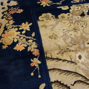 Navy blue border with coral and gold florals surrounds a detailed beige scenic field on rustic wood.