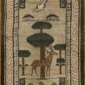 Tan rug with dark pictorial motifs of a deer and trees, bordered by brown and beige geometric fretwork.