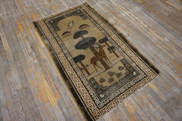 Rustic brown and beige rug with a deer and tree design rests on distressed gray wood planks.