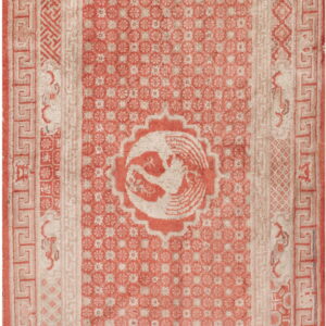 Distressed coral and beige rug with a complex Greek key border and a central round bird design.