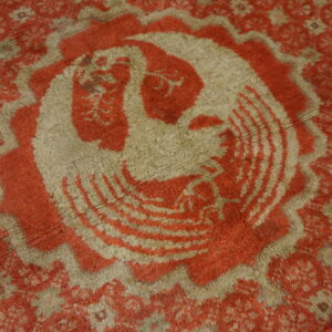 Plush, shaggy rug in muted red and beige with a large stylized bird medallion design.