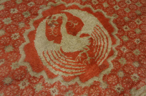 Plush, shaggy rug in muted red and beige with a large stylized bird medallion design.