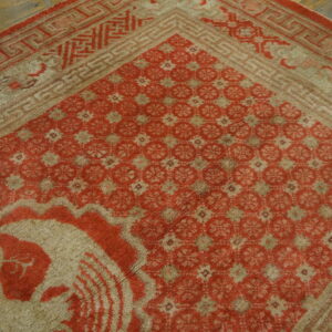 Faded red and tan high-pile rug with geometric patterns visible on rustic wooden floorboards.