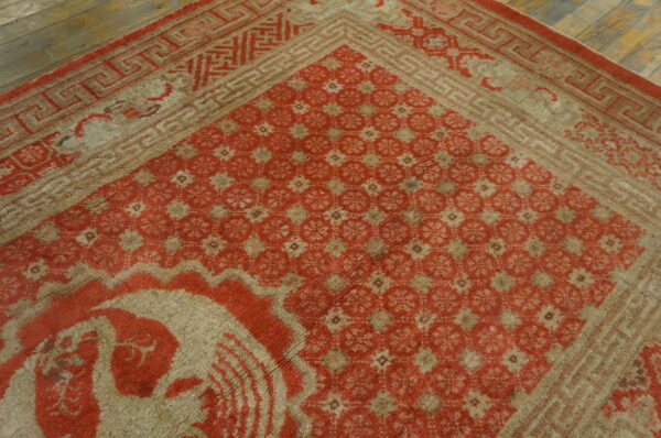 Faded red and tan high-pile rug with geometric patterns visible on rustic wooden floorboards.