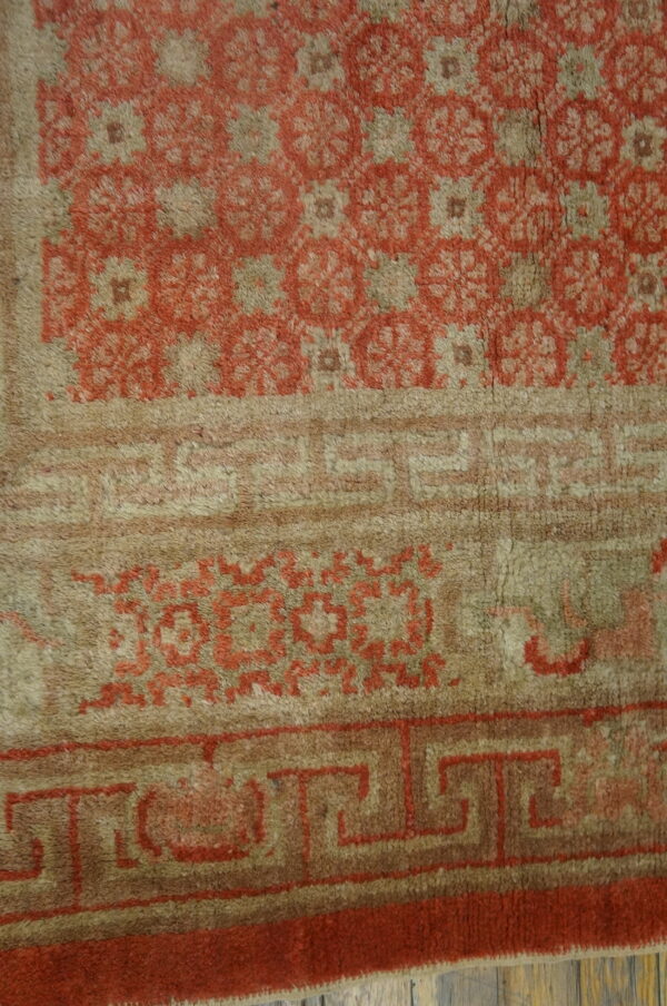 Close-up of a high-pile rug featuring terracotta floral medallions and geometric borders on a taupe background.
