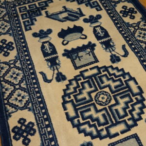 Traditional cream rug with rich blue borders and symbolic central designs on rustic hardwood flooring.