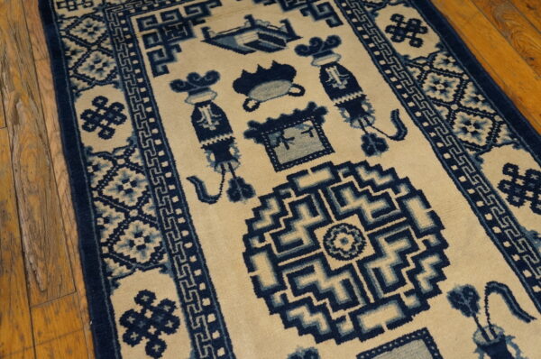 Traditional cream rug with rich blue borders and symbolic central designs on rustic hardwood flooring.