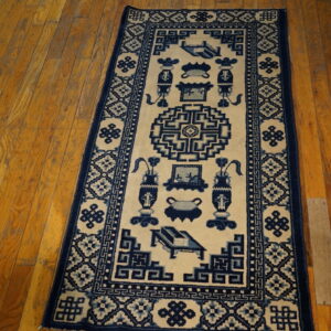 A long runner rug featuring indigo blue geometric and vessel designs on a cream field on wood floors.