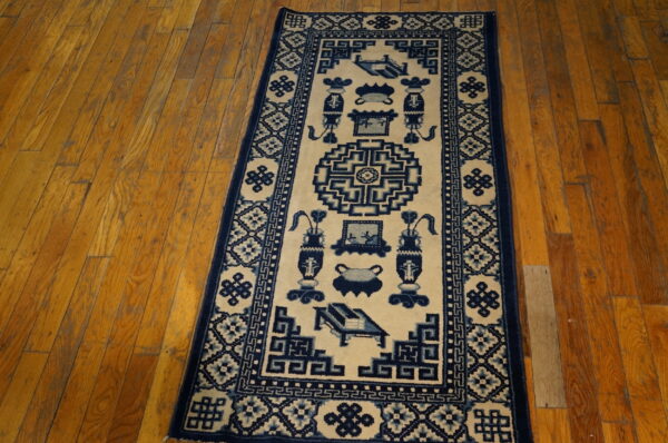 A long runner rug featuring indigo blue geometric and vessel designs on a cream field on wood floors.