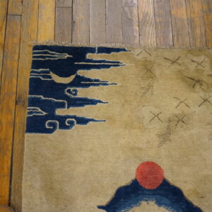 Beige rug with blue crescent moon and cloud motifs next to rustic orange wood flooring.