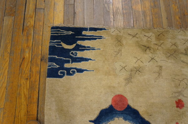 Small scenic pictorial antique chinese bird design baotou area rug 4 Beige rug with blue crescent moon and cloud motifs next to rustic orange wood flooring.