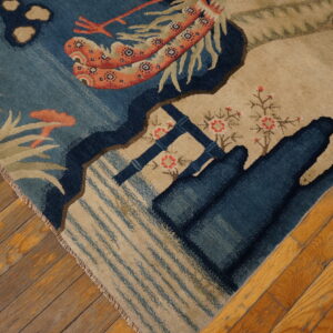 Detail of a blue and tan patterned rug with red and coral accents lying on distressed wood planks.