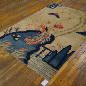Beige rug with a blue pond and coral mythological bird motif rests on wood plank flooring.