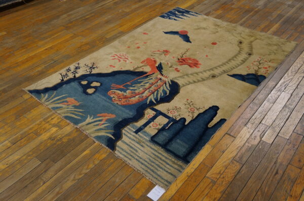 Small scenic pictorial antique chinese bird design baotou area rug 3 Beige rug with a blue pond and coral mythological bird motif rests on wood plank flooring.