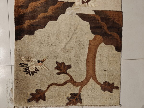 Beige and brown pictorial rug featuring a tree branch and flying bird motif on light tiled flooring.