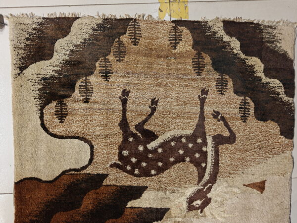A shaggy brown and tan rug featuring a stylized deer pattern sits on white tiled floor.