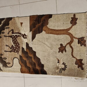 Tan and brown rug featuring a pictorial wildlife scene with a running deer, tree, and bird.