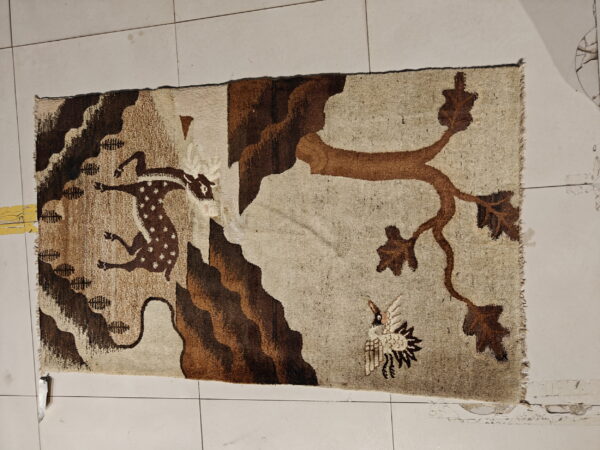 Tan and brown rug featuring a pictorial wildlife scene with a running deer, tree, and bird.