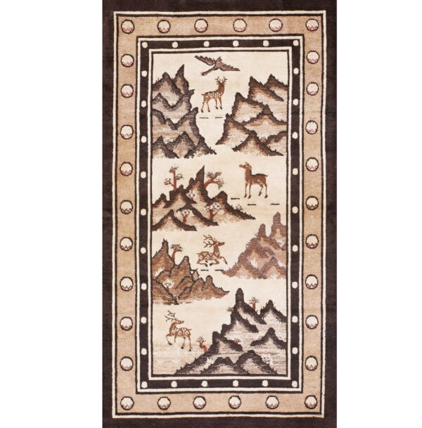 Brown and beige area rug depicting a mountain landscape with deer and birds inside a striped border.