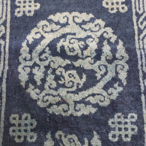 Dark blue high-pile rug featuring a circular traditional pattern and geometric motifs in faded light gray.