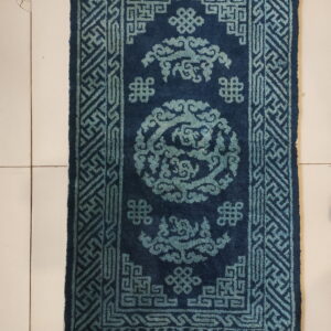 Deep blue rug with teal geometric and cloud patterns displayed on a light tiled floor.