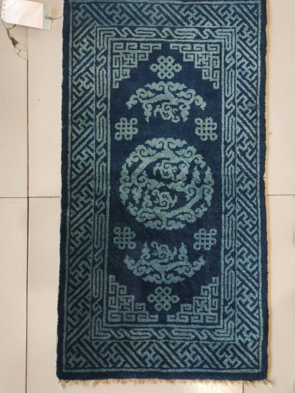 Deep blue rug with teal geometric and cloud patterns displayed on a light tiled floor.