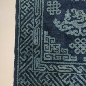 Deep blue pile rug featuring light teal geometric and cloud motifs on a cream-colored floor.