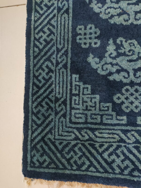 Deep blue pile rug featuring light teal geometric and cloud motifs on a cream-colored floor.