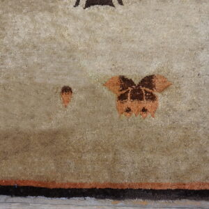Textured tan rug with dark brown and burnt orange abstract patterns and a thick dark border.