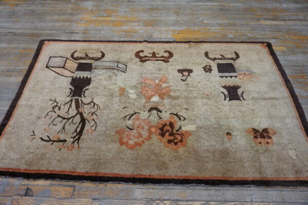 Greige rug with dark brown and coral figural patterns rests upon worn gray wood planks.