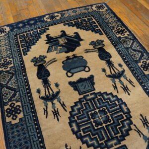 Tan and blue geometric patterned rug with stylized motifs on distressed plank hardwood flooring.