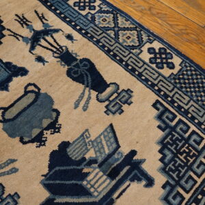 Beige and blue patterned rug showing symbolic designs and geometric borders on wood floor planks.