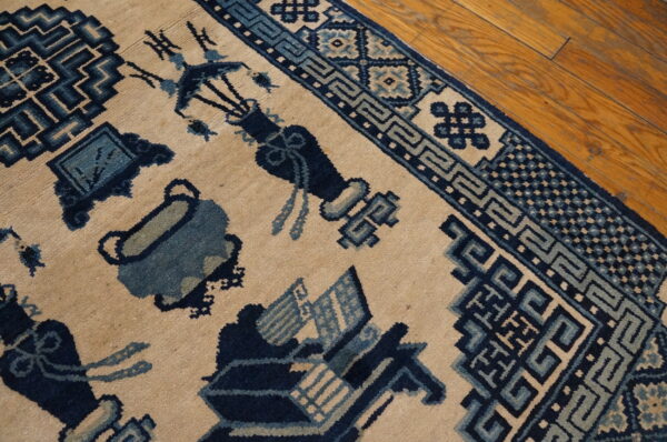 Beige and blue patterned rug showing symbolic designs and geometric borders on wood floor planks.